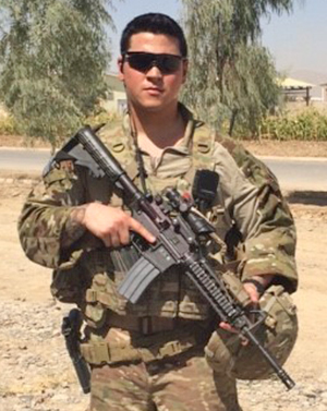 Photo of Joseph Otake dressed in Army camouflage with rifle.