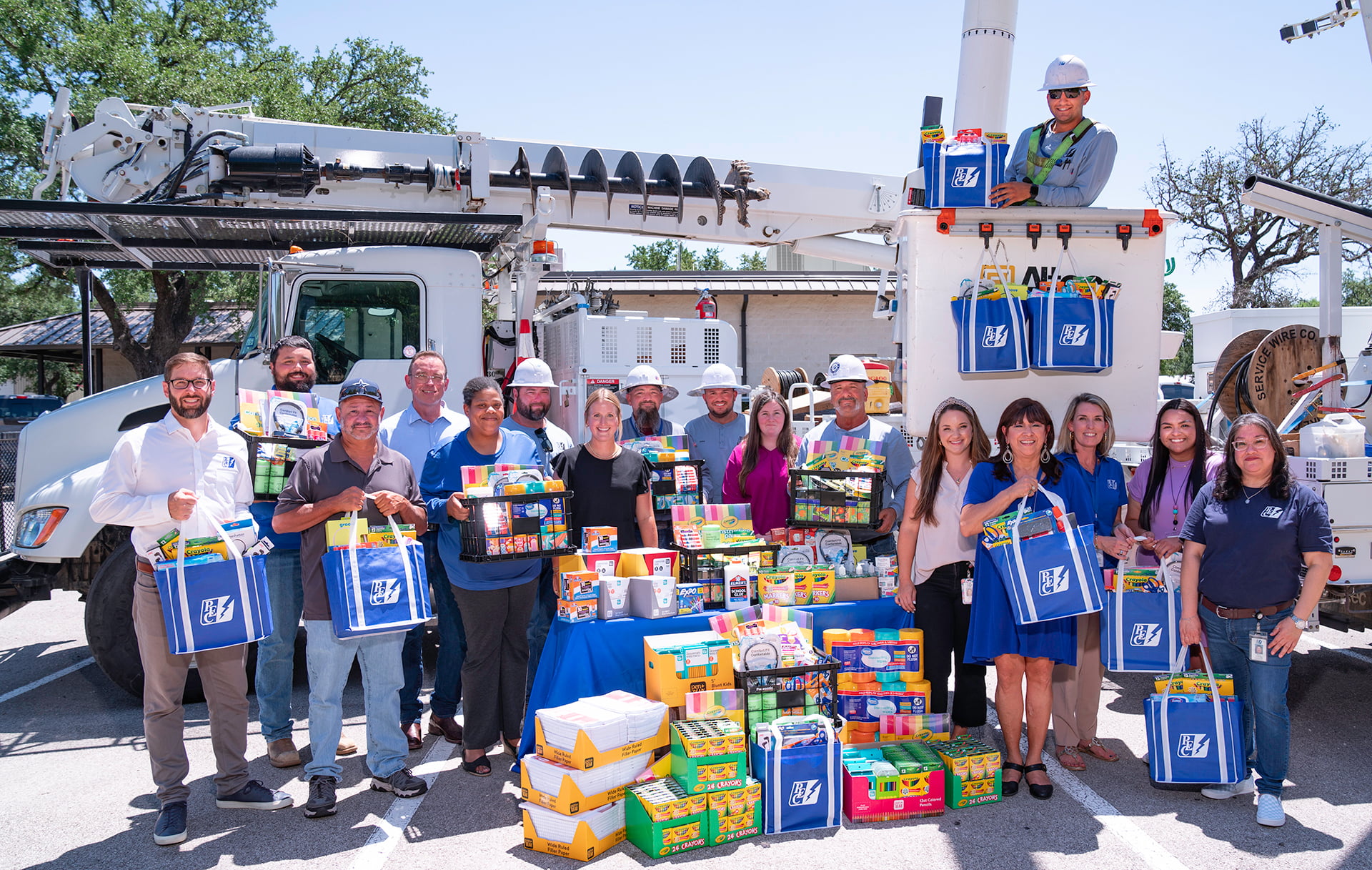 PEC employees standing in from of bucket truck with school supplies
